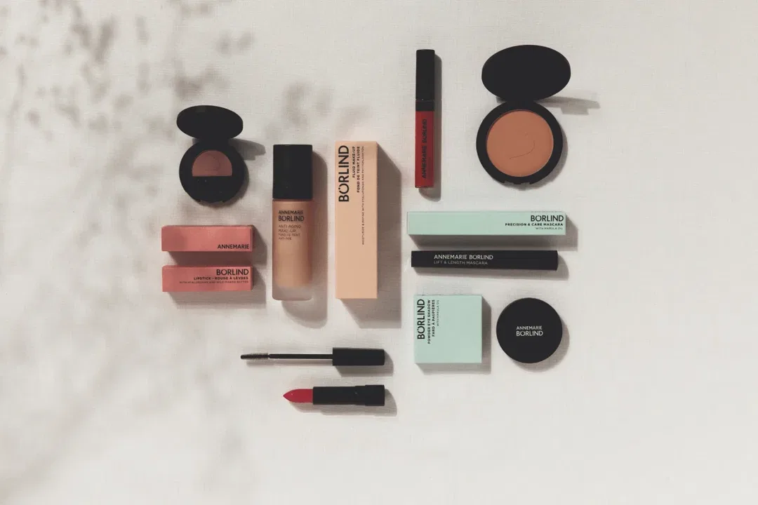 ANNEMARIE BÖRLIND Make-up mit Foundation, Lippenstift, Mascara, Puder und Rouge auf hellem Hintergrund